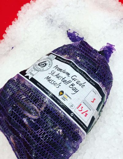 Suppliers & Producers - Image of a bag of St Austell mussels in a purple net bag on a bed of ice.